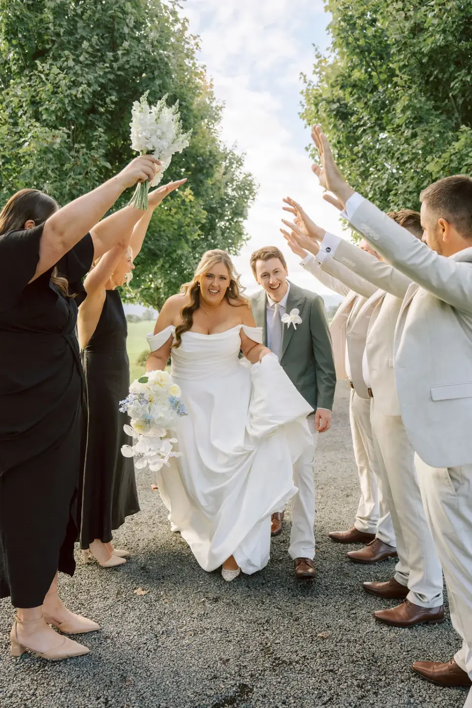 Wedding guests cheering a couple through an archway of raised hands — an example photo from a real wedding