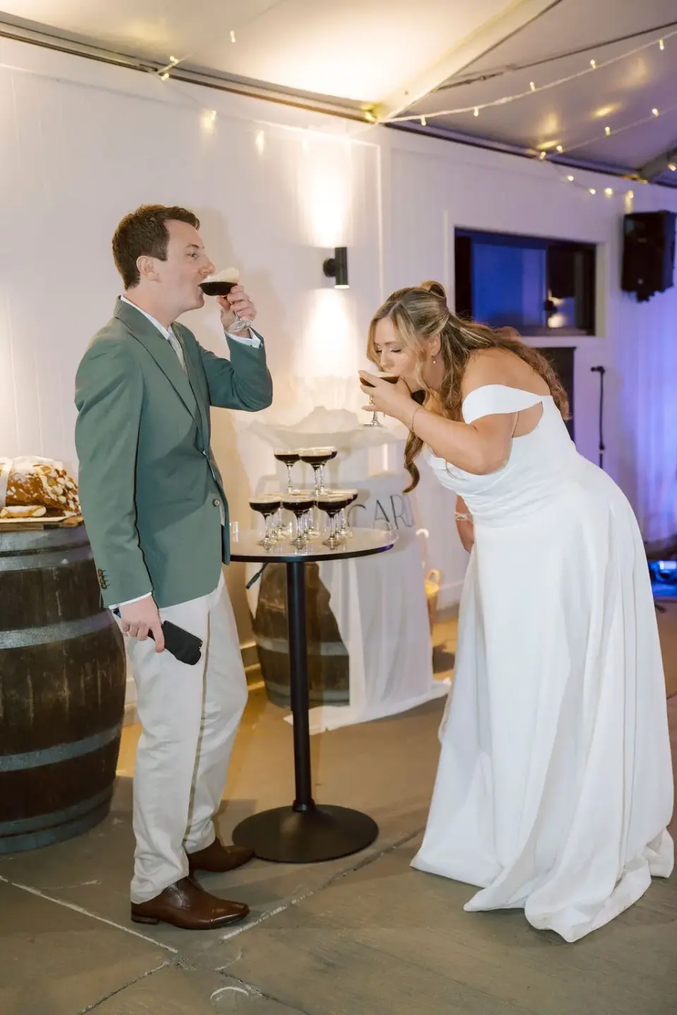 The couple drinking espresso martinis from a coupe tower at their reception