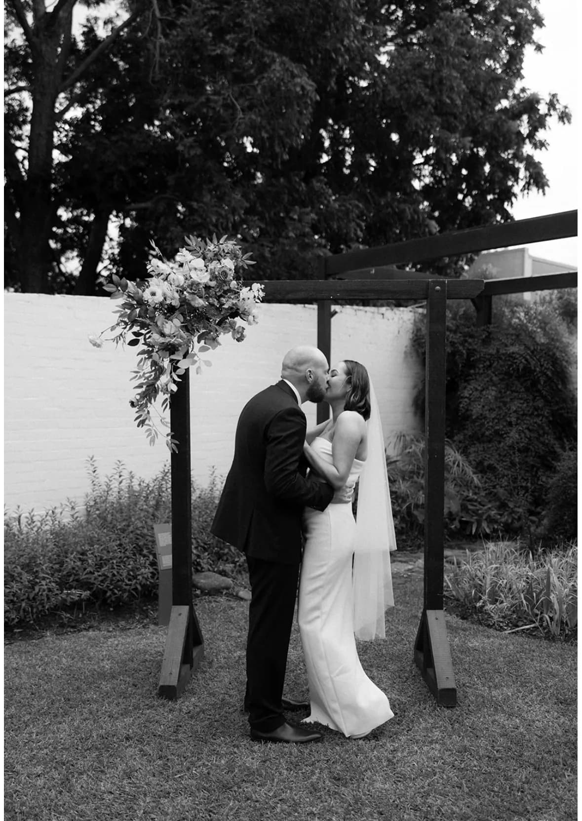 Bride and groom kissing under arbour in Penrith venue