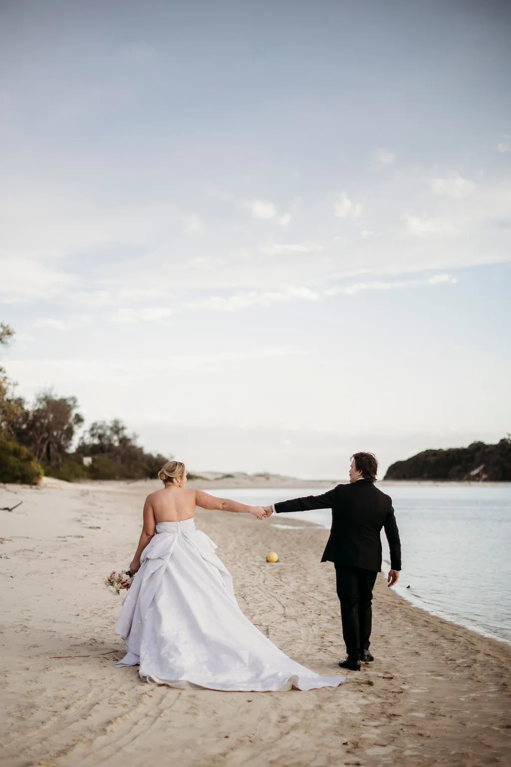 Bride and groom walking hand in hand along the beach at The Cove Jervis Bay