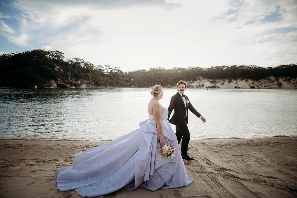 Bride and groom walking hand in hand on the beach at The Cove Jervis Bay