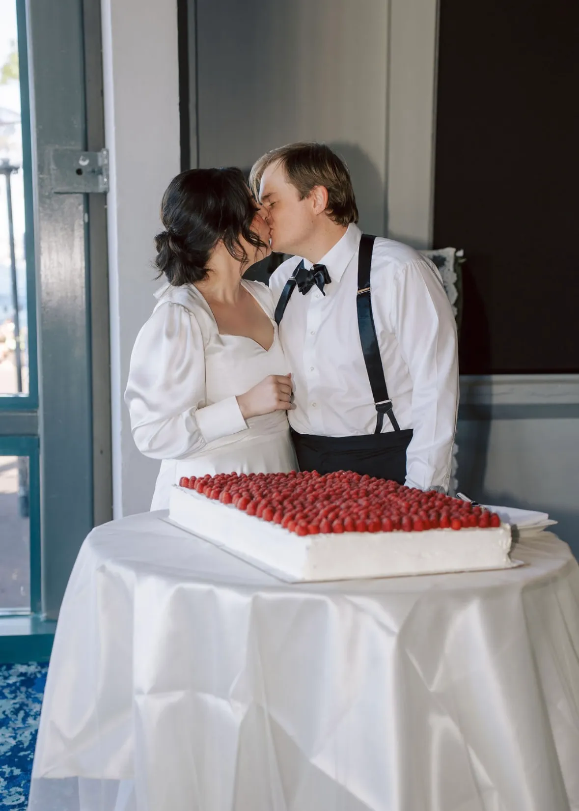 Bride and groom kissing with raspberry wedding cake at Sydney venue