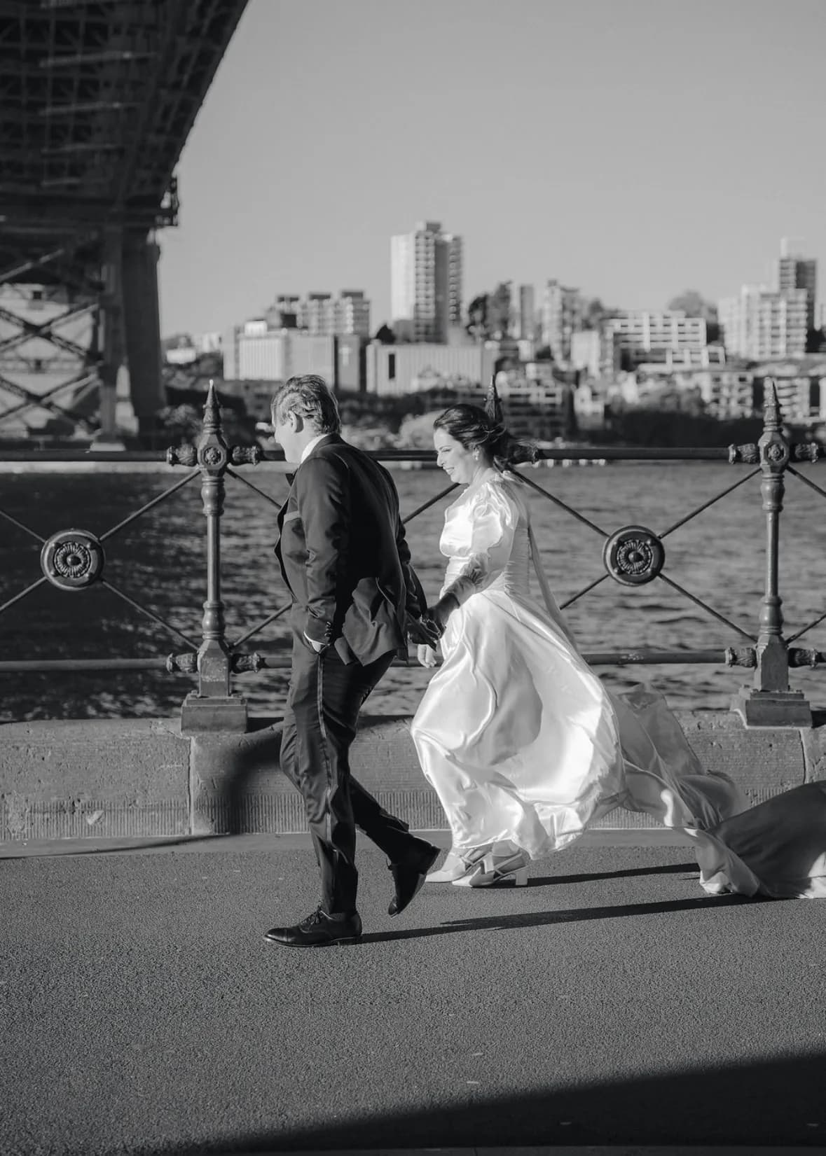 Bride and groom walking hand in hand near Sydney Harbour bridge